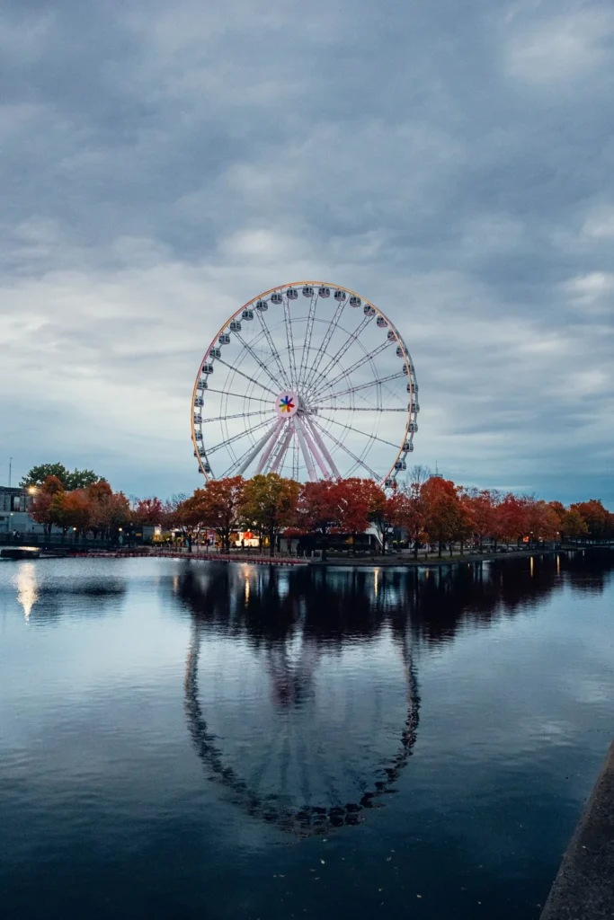 Ferris wheel reflected in still water at the Old Port of Montreal under a cloudy autumn sky