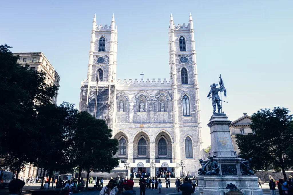 Notre-Dame Basilica and Place d’Armes photographed on a sunny day in Montreal.