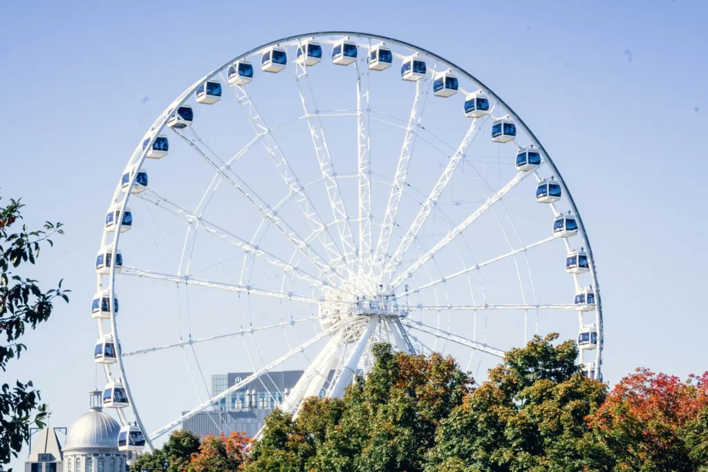La Grande Roue de Montréal framed by trees and summer flowers at the Old Port.