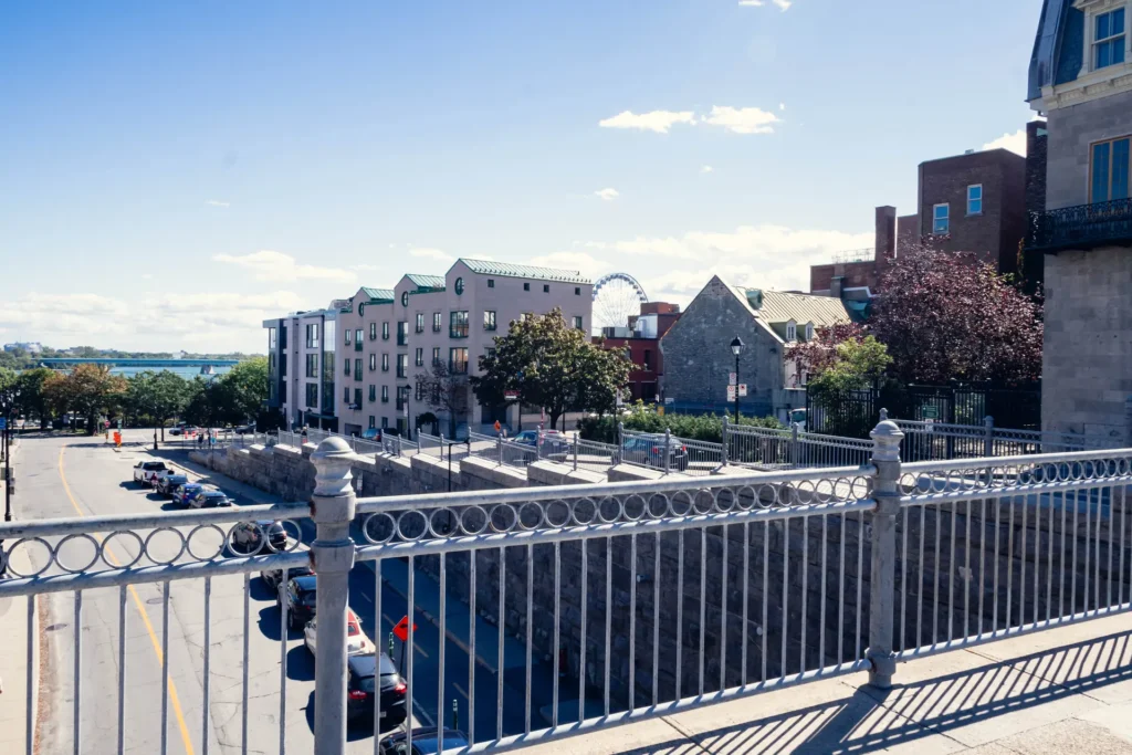 Summer waterfront view at the Old Port of Montreal with historic buildings beyond the railing.