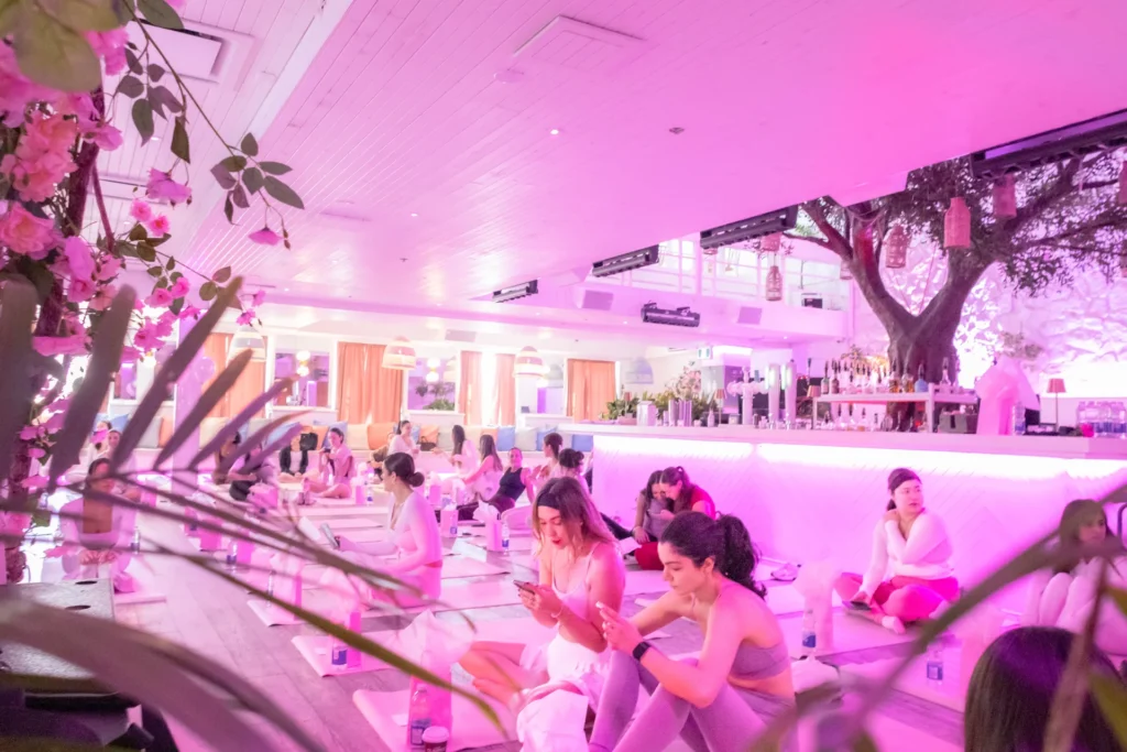 Wide view of a Pangea Pilates event in Montreal with pink lighting and participants on reformers.